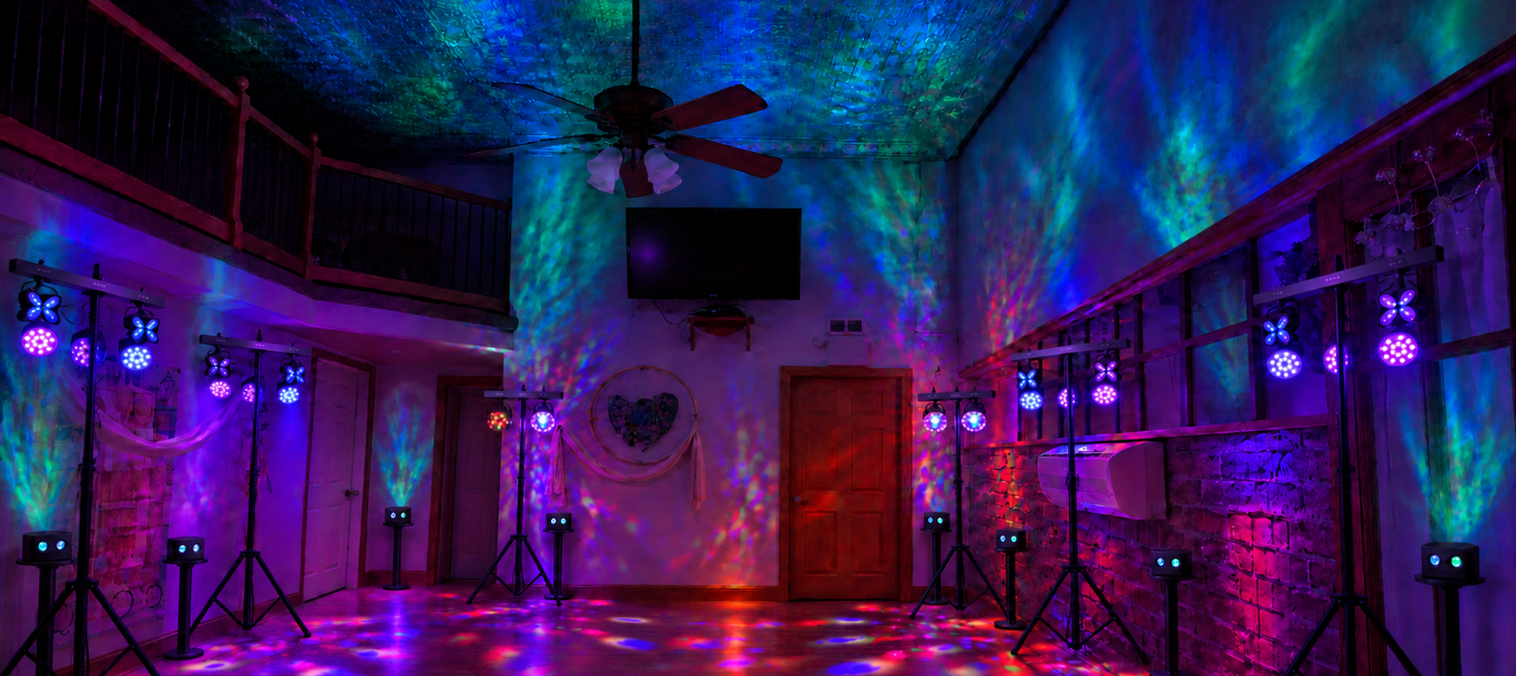 The Cave with colorful lighting, a high ceiling, and lights on freestanding stands